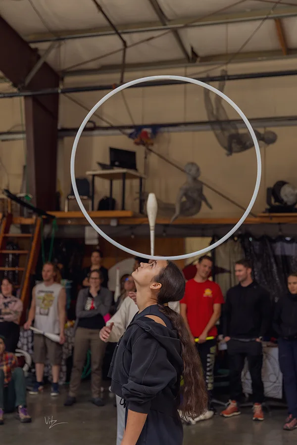 all eyes are on her as she balances a hoop on her face attentively